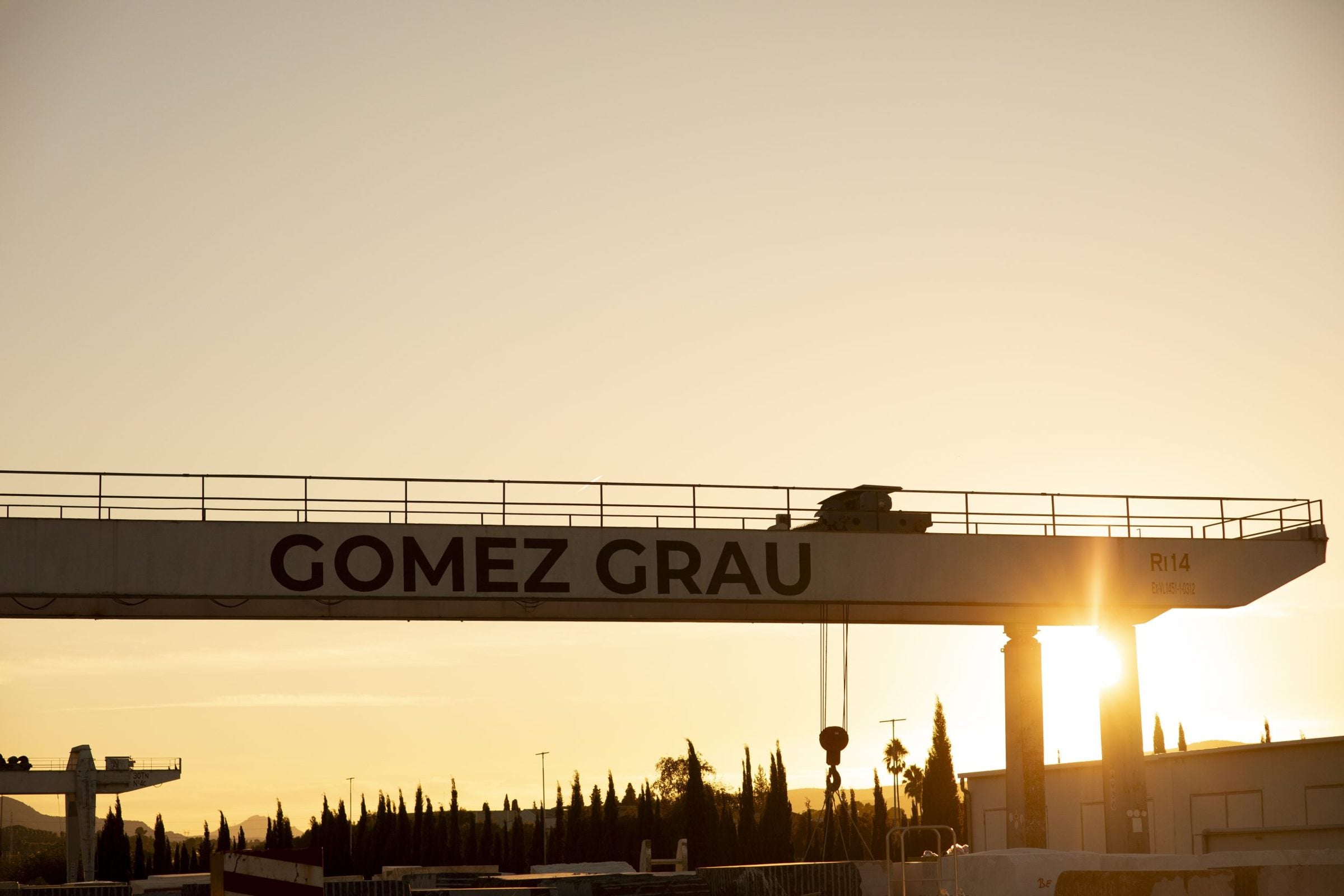Puente grúa con el rótulo de Gómez Grau al atardecer